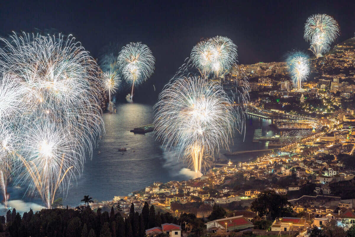 Passagem do Ano O evento da Passagem de Ano no Funchal, na Ilha da Madeira, é famoso mundialmente pelo seu espetacular fogo de artifício, que ilumina o céu sobre o Porto do Funchal e atrai visitantes de todo o mundo. O fogo de artifício é o ponto alto da celebração, conhecido por ser um dos mais grandiosos do mundo. A exibição pirotécnica é lançada de várias plataformas ao redor da baía, criando um espetáculo deslumbrante que pode ser visto de vários pontos da cidade Durante a Passagem de Ano, o Funchal se transforma em uma festa vibrante, com música ao vivo, eventos de jantar e festa, e uma atmosfera de celebração que se espalha por toda a cidade. Hotéis e restaurantes oferecem jantares de gala e festas especiais para marcar a ocasião Para quem planeja visitar o Funchal durante a Passagem de Ano, é aconselhável reservar alojamento com antecedência, pois os hotéis tendem a ficar lotados rapidamente devido à popularidade do evento. A Passagem de Ano no Funchal é uma experiência única que combina a beleza natural da Madeira com uma celebração inesquecível, proporcionando um início de ano novo cheio de cores, alegria e esperança.